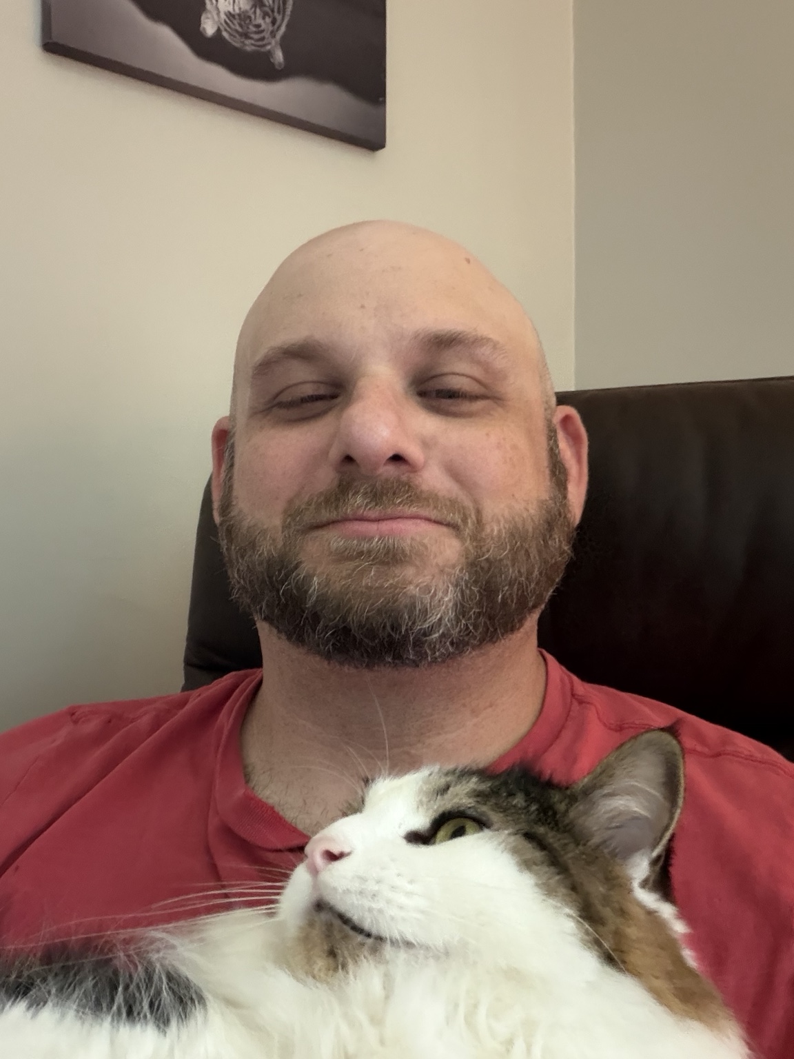Joseph relaxing at home with one of his cats looking up at him