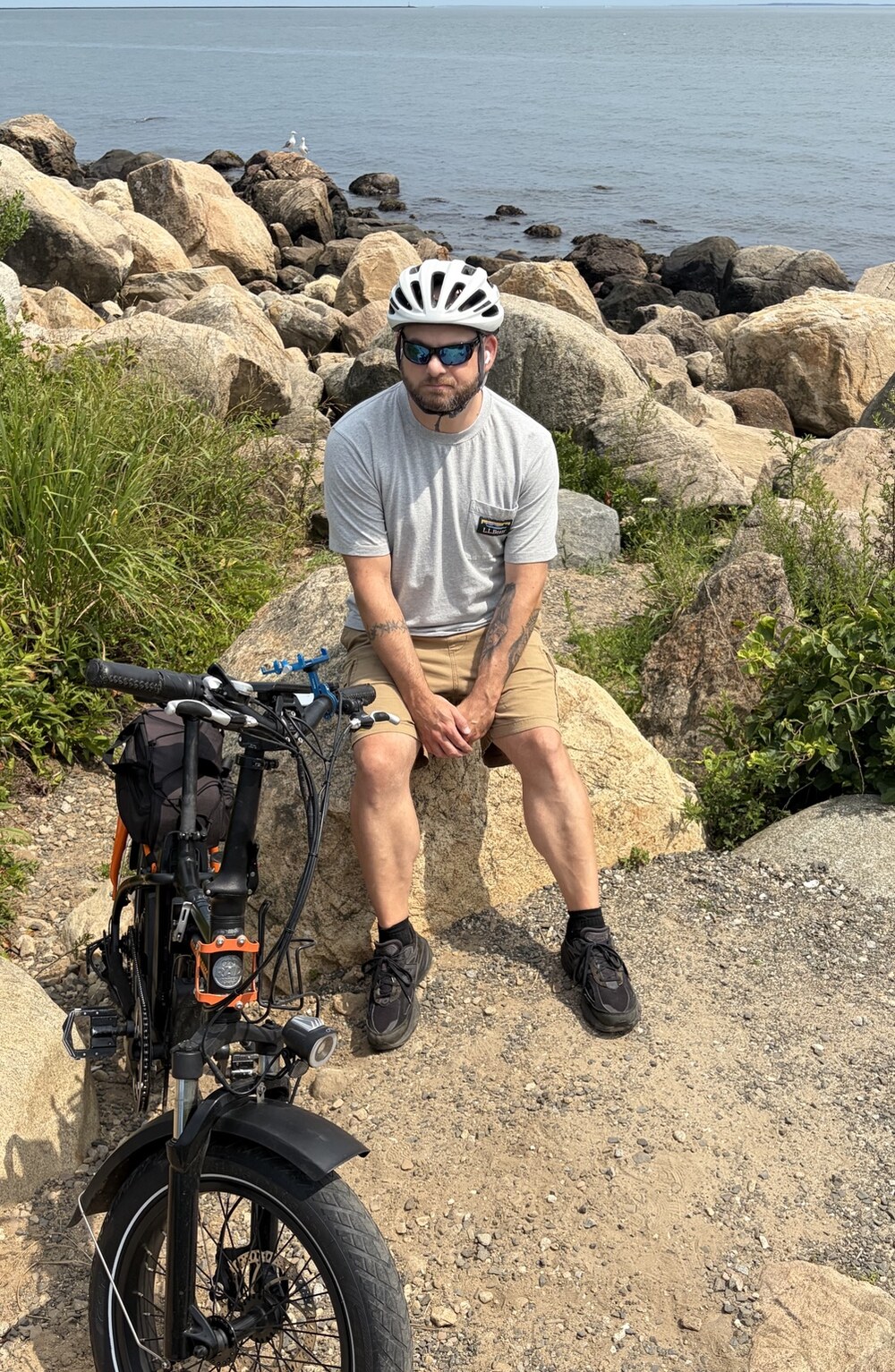 Joseph taking a break beside his bicycle near the shore